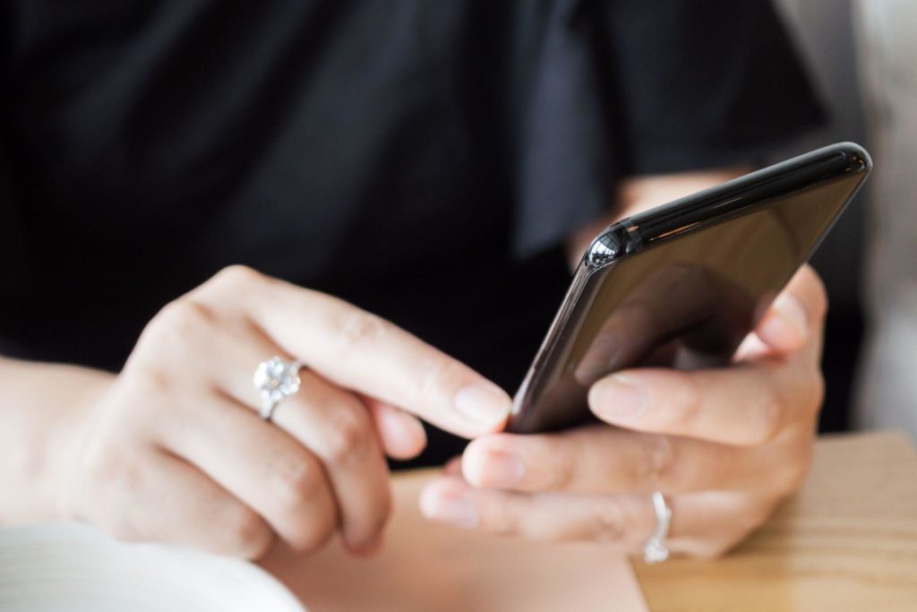Woman with diamond ring on hand using smartphone in cafe restaurant