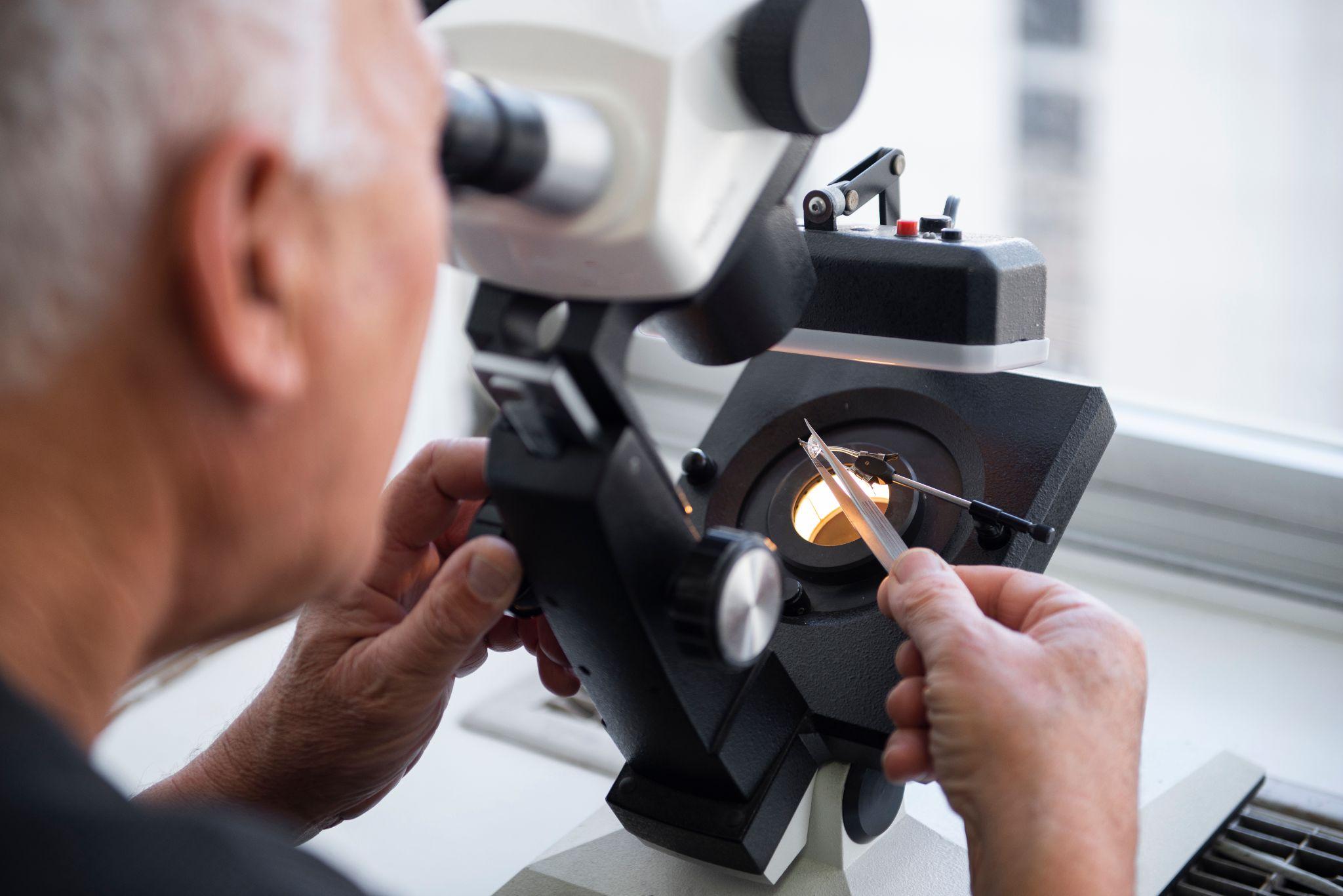 A gemologist looks at a diamond through a microscope, gemstones appraisal.
