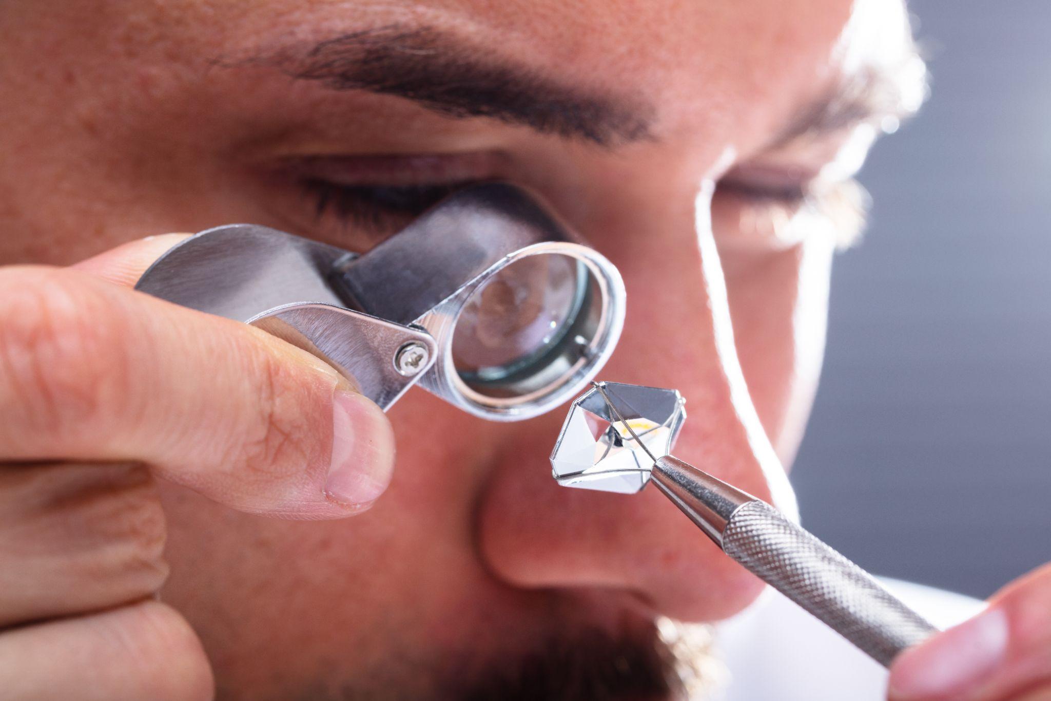 Jeweler looking at diamond through magnifying loupe