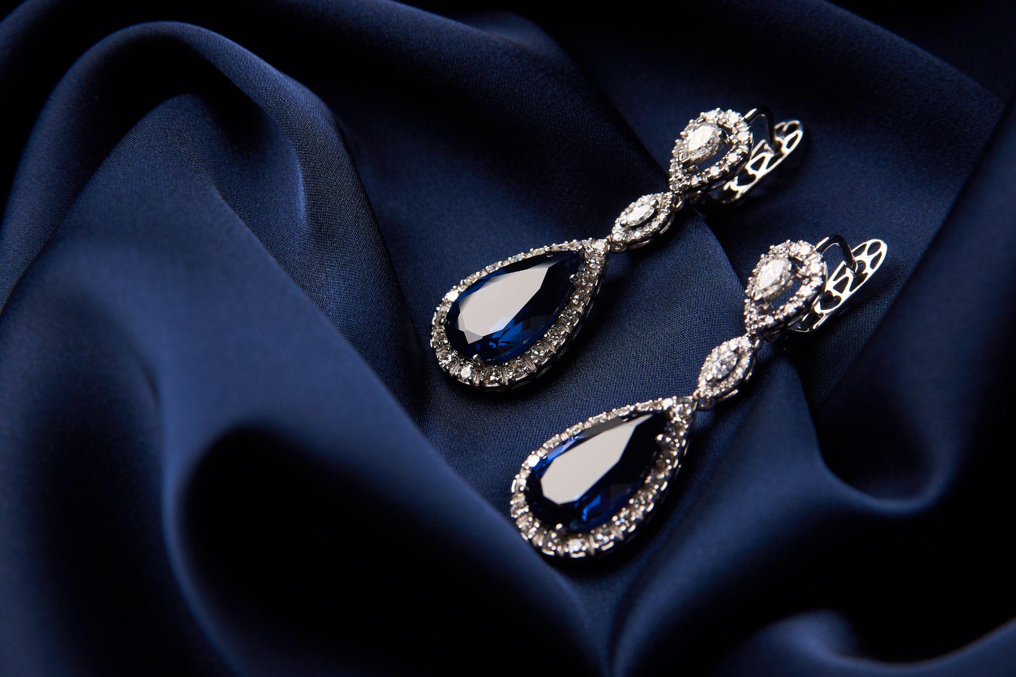 two diamond earrings on navy blue silk